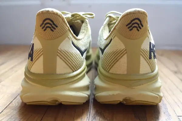 The back of two Hoka Clifton 9 sneakers on a wooden floor