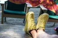 Two legs crossed on wood while wearing Hoka Clifton 9 sneakers