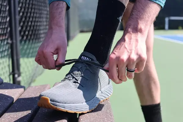 A close-up of a person tying a NOBULL Men