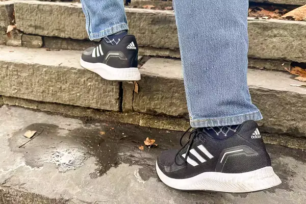 Person walking up stairs wearing gray Adidas Men