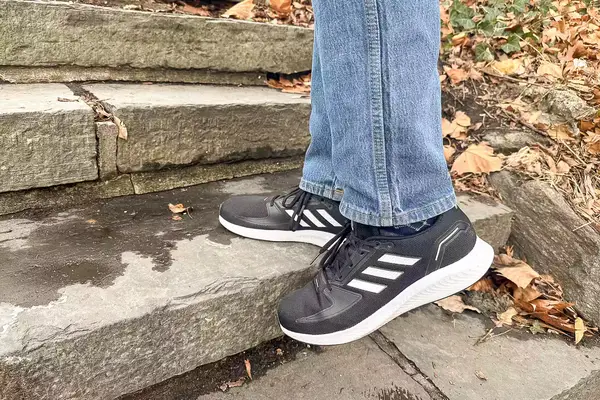 Person walking up stairs wearing gray Adidas Men