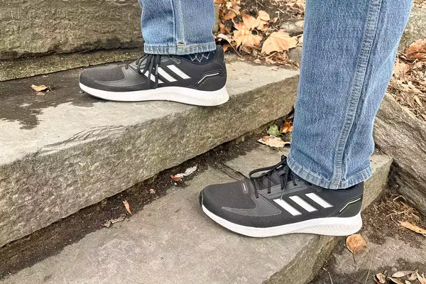 Person walking up stairs wearing gray Adidas Men