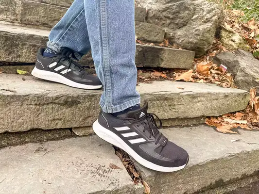 Person walking down stairs wearing gray Adidas Men