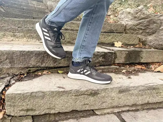 Person walking down stairs wearing gray Adidas Men