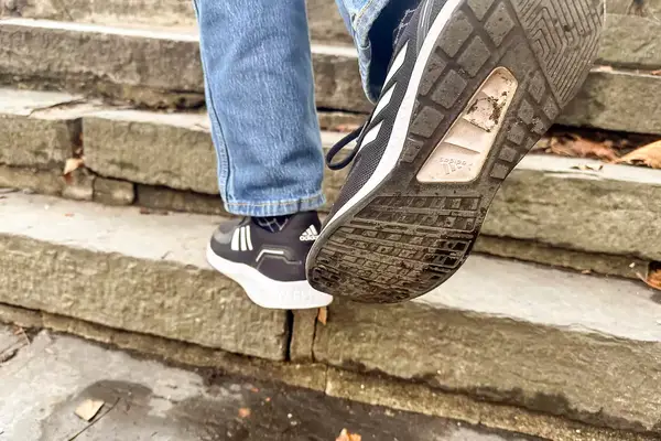 Person walking up stairs wearing gray Adidas Men