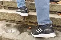 Person walking up stairs wearing gray Adidas Men