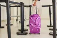 A person wheeling the Vera Bradley Adair Rolling Duffel Bag through a barricade