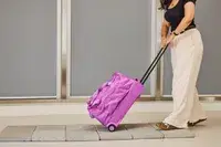A person wheeling the Vera Bradley Adair Rolling Duffel Bag on tiles