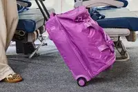 A person wheeling the Vera Bradley Adair Rolling Duffel Bag through an aisle