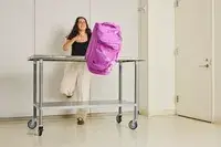 A person pushing the Vera Bradley Adair Rolling Duffel Bag off of a counter