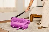 A person hitting the Vera Bradley Adair Rolling Duffel Bag with a bat