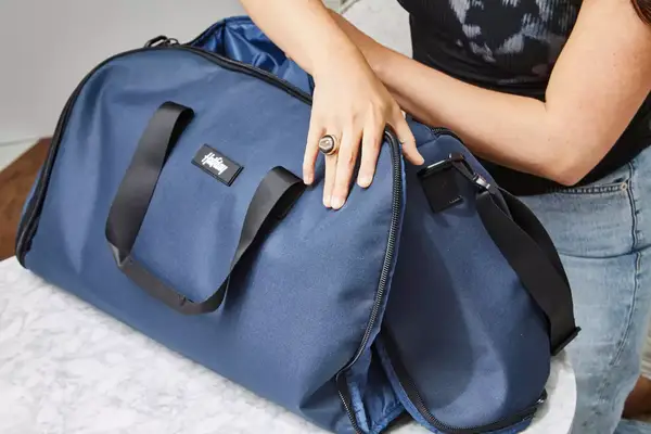 A person zips up the Halfday The Garment Duffel