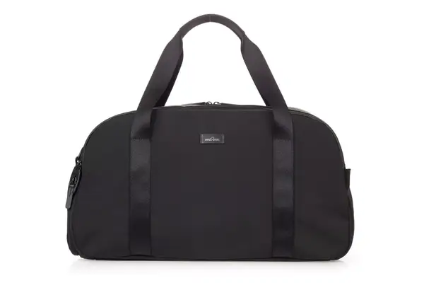 Hand on suitcase handle holding Béis The Weekender Travel Bag