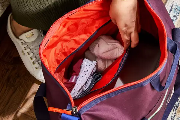 Hand reaching into a filled Cotopaxi Viaje 35L Weekender Bag - Cada Día