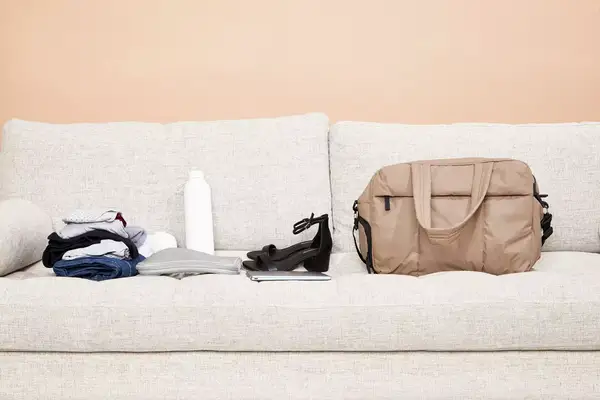 Calpak Luka Duffel Bag displayed on a couch next to items to be packed