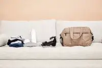 Calpak Luka Duffel Bag displayed on a couch next to items to be packed