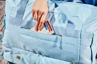 A hand slipping a wallet into the ETRONIK Large Overnight Weekender 55L