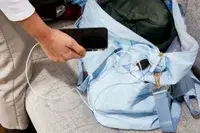 Hand holding a phone plugged into the ETRONIK Large Overnight Weekender 55L