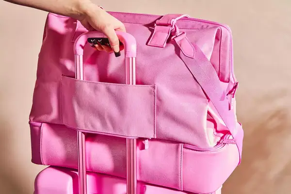 Hand on suitcase handle holding Béis The Weekender Travel Bag