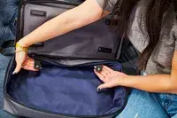 Two hands holding the straps on the Travelpro x Travel & Lanetrek Drop-bottom Weekender Bag