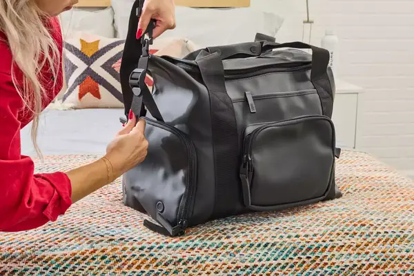 A person adjusts the strap on the Rains Large Texel Kit Bag