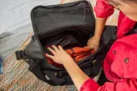 A person places clothing inside the Rains Large Texel Kit Bag