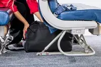 A person places the Rains Large Texel Kit Bag under the seat in front of them