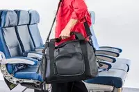 A person wears the Rains Large Texel Kit Bag by the shoulder strap