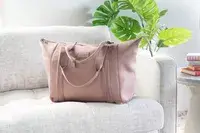 Hand opening the bottom compartment of Béis The Weekender Travel Bag on white floor