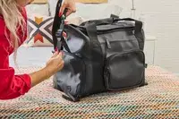 A person adjusts the strap on the Rains Large Texel Kit Bag