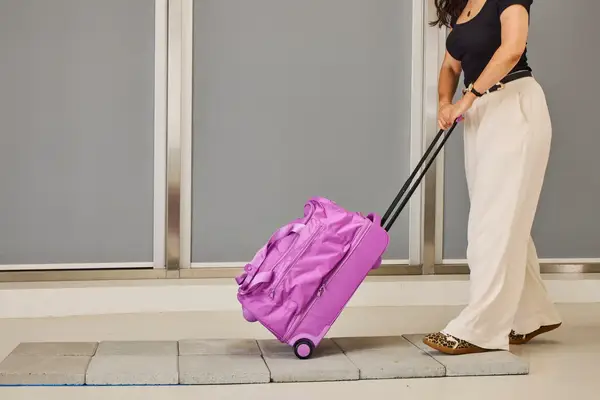 A person wheeling the Vera Bradley Adair Rolling Duffel Bag on tiles