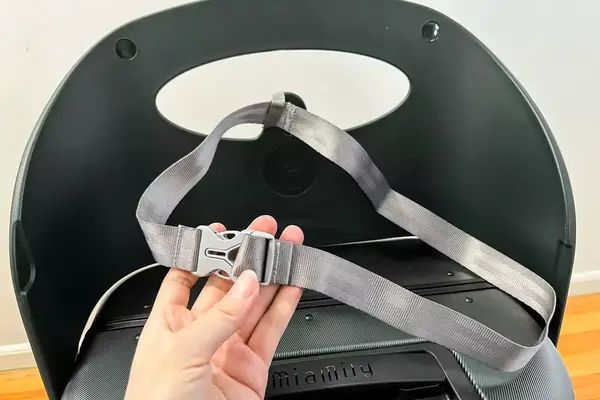A hand holding the seatbelt of the MiaMily Carry-On