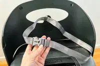 A hand holding the seatbelt of the MiaMily Carry-On