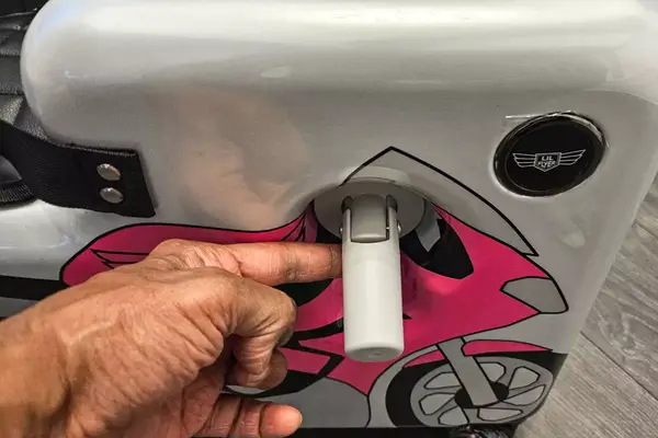 A ahnd touching a handle of the Younglingz Ride On Suitcase