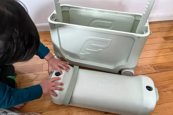 A child placing the lid of the ​​Stokke JetKids BedBox on the floor next to the box