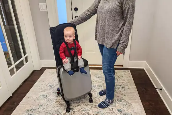 A baby sitting on the Mountain Buggy Skyrider Luxury as an adult holds the handle