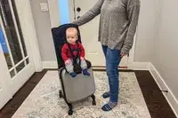 A baby sitting on the Mountain Buggy Skyrider Luxury as an adult holds the handle