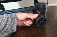 A hand touching the wheel of the Mountain Buggy Skyrider Luxury
