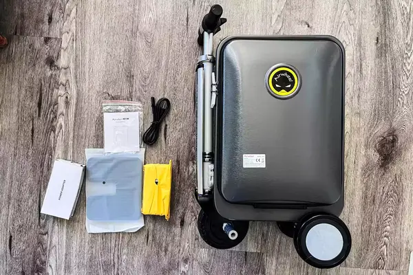The Airwheel SE3S Smart Rideable Suitcase Scooter and accessories on a wooden floor