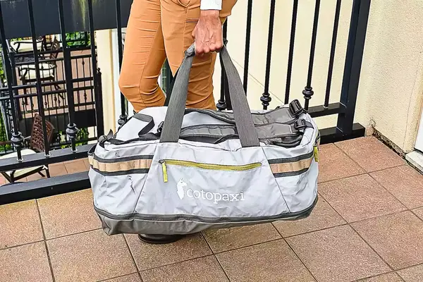 Person holding a Cotopaxi Allpa Getaway 70L Duffel by its strap