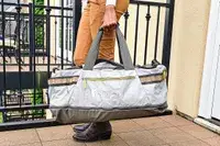 Person holding a Cotopaxi Allpa Getaway 70L Duffel, standing outside on a balcony