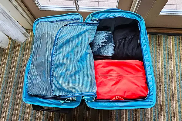 An open Cotopaxi Allpa 65L Roller Bag with organized packing cubes and clothes