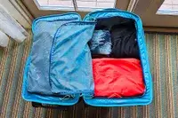 An open Cotopaxi Allpa 65L Roller Bag with organized packing cubes and clothes