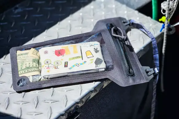 Items in the Nite Ize RunOff Waterproof Phone Case resting on a metal surface