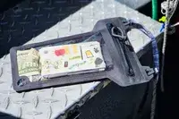 Items in the Nite Ize RunOff Waterproof Phone Case resting on a metal surface