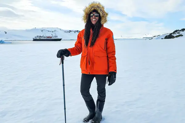 Woman posing on ice in Antarctica with hiking pole