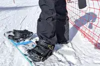 A close-up of a person stepping onto a snowboard while wearing the Burton Women’s AK Summit GORE-TEX 2L Pants
