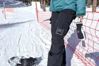 A person leaning on a red fabric fence while wearing the Burton Women’s AK Summit GORE-TEX 2L Pants