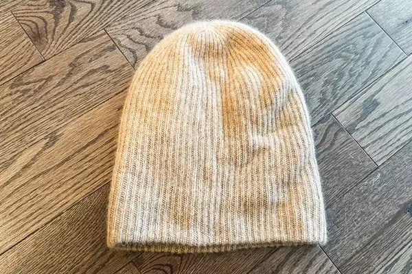 The White + Warren Cashmere Beanie on a wood background