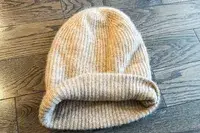 The White + Warren Cashmere Beanie laid on a wood background